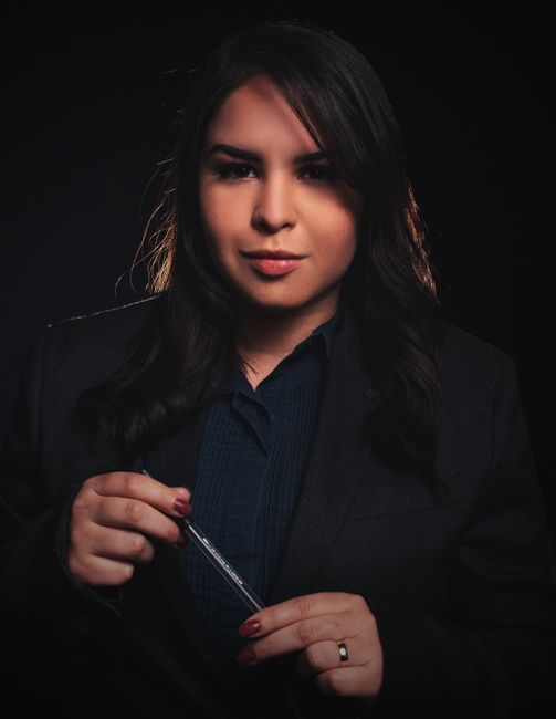Priya Nair, reviewer — professional headshot of an elegant businesswoman with dark hair holding a pen.