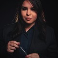 Priya Nair, reviewer — professional headshot of an elegant businesswoman with dark hair holding a pen.