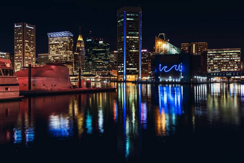 Baltimore skyline at night reflecting on Inner Harbor water