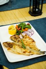 Grilled fish served with fresh salad and lemon