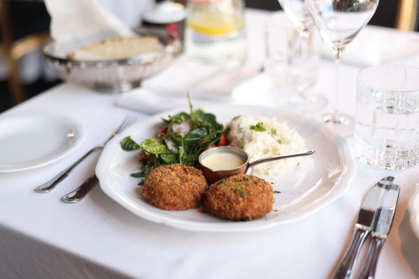 Crab cakes plated with salad and rice in a restaurant setting
