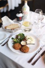 Close-up of crab cakes with salad on a white tablecloth