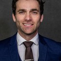 Marcus Bell, reviewer — professional headshot of a smiling man in a blue suit and tie.