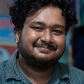 Tom Kowalski, reviewer — professional headshot of a smiling man with curly hair in a casual checkered shirt.