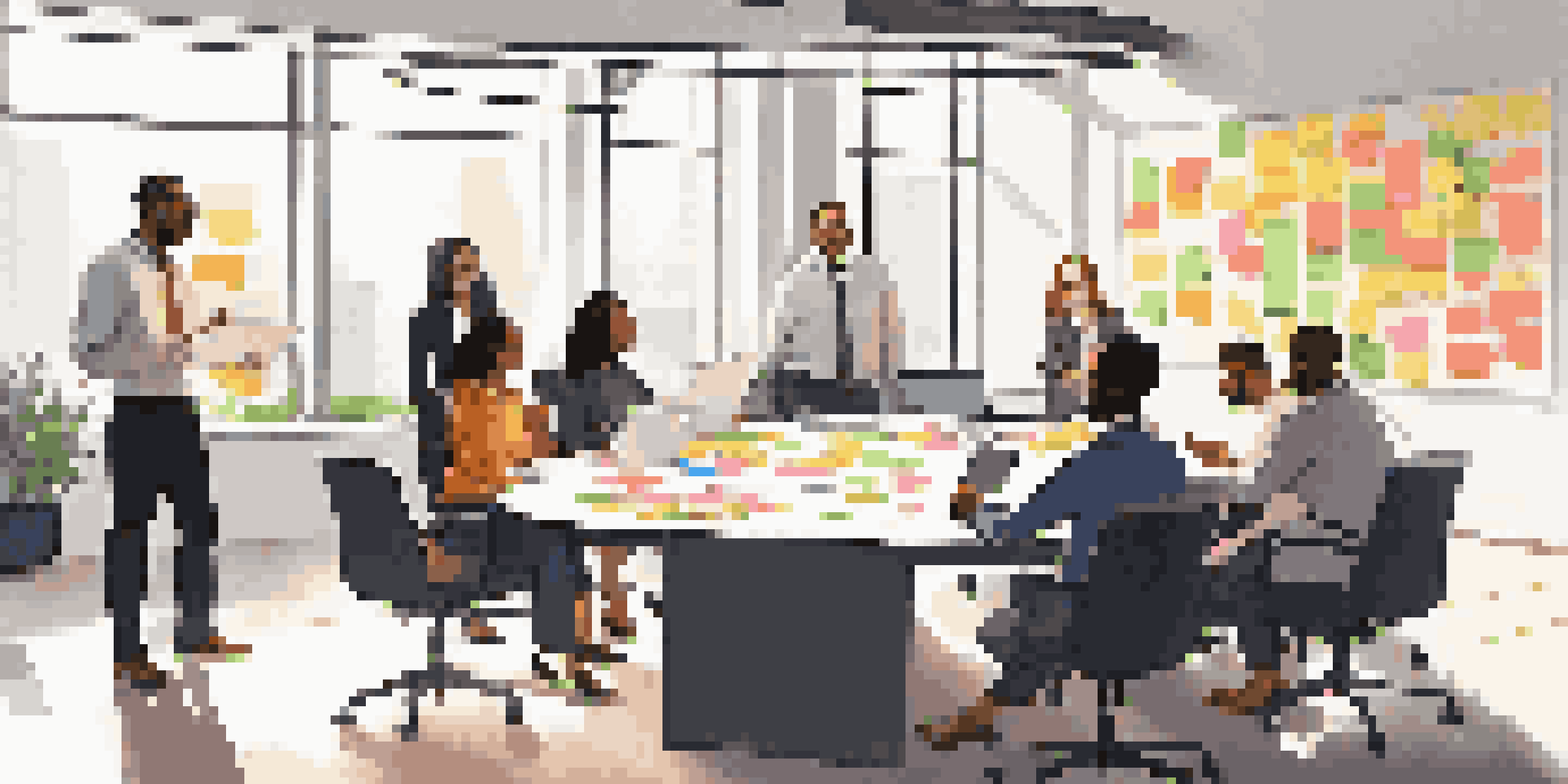 A diverse group of sales team members collaborating around a round table in a bright office, with sticky notes and a whiteboard visible.