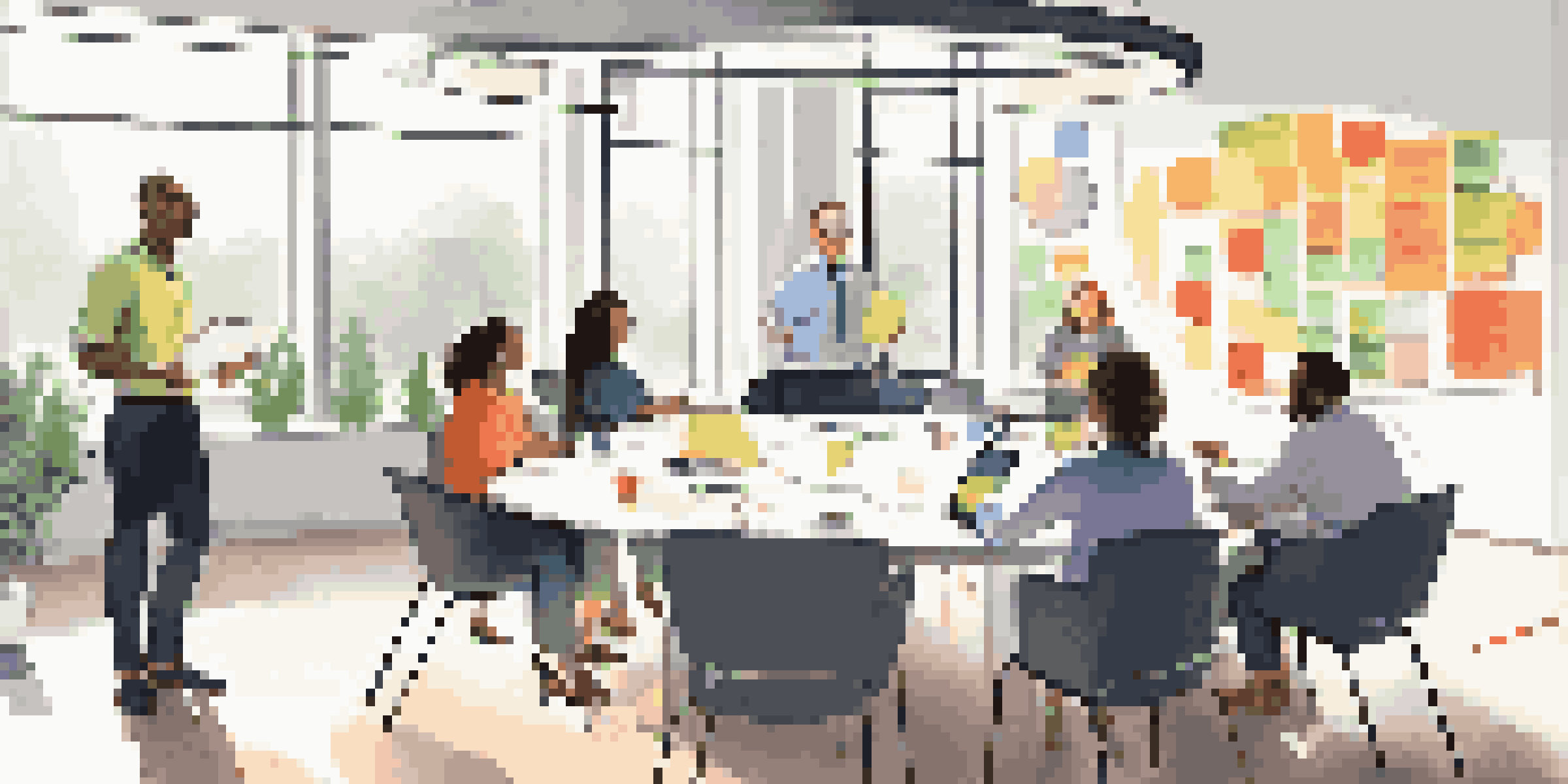 A diverse team of professionals in a bright office discussing feedback around a circular table with sticky notes and a whiteboard in the background.