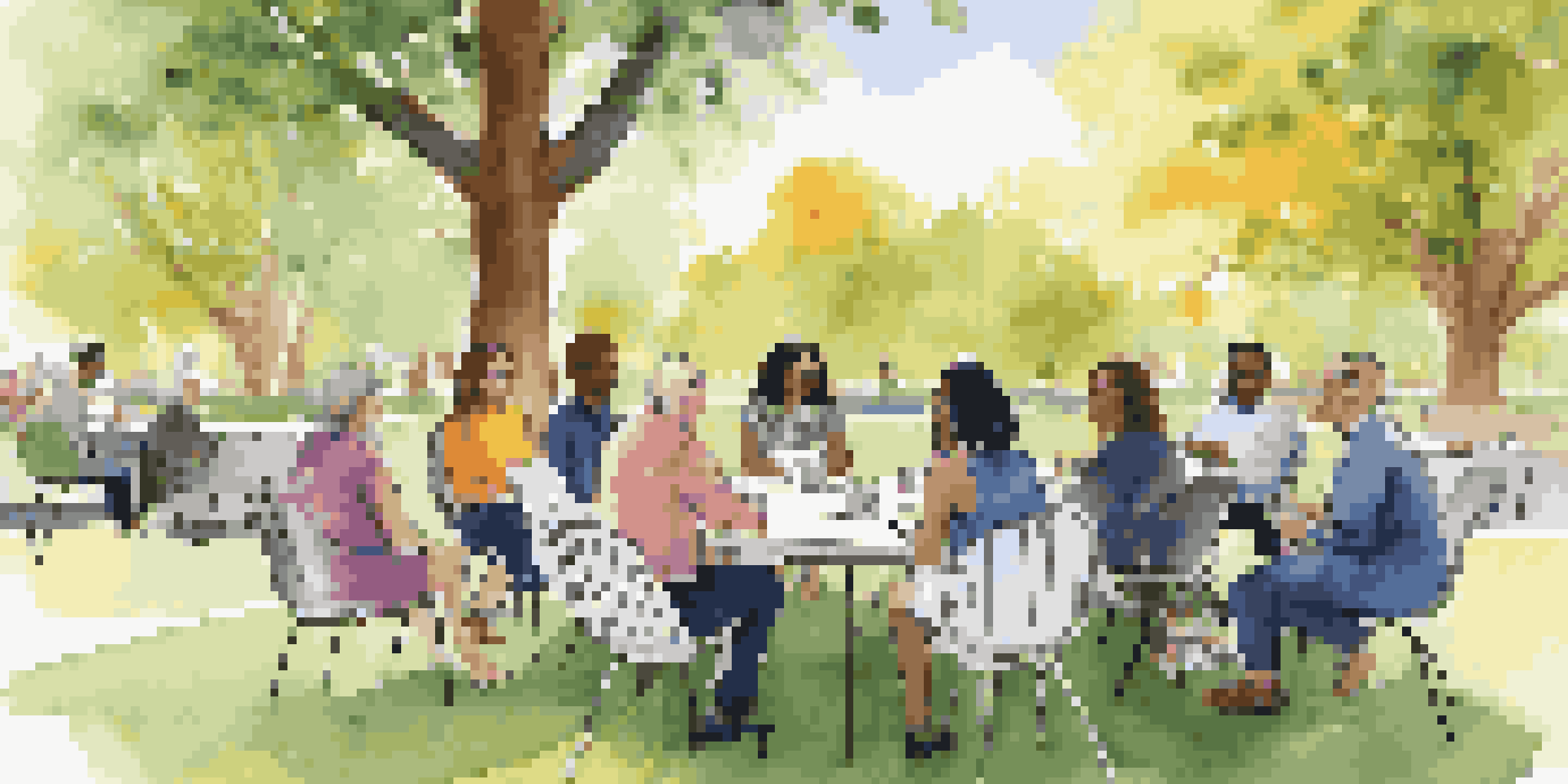 A diverse group of stakeholders having a meeting outdoors around a round table in a park, surrounded by greenery and flowers.