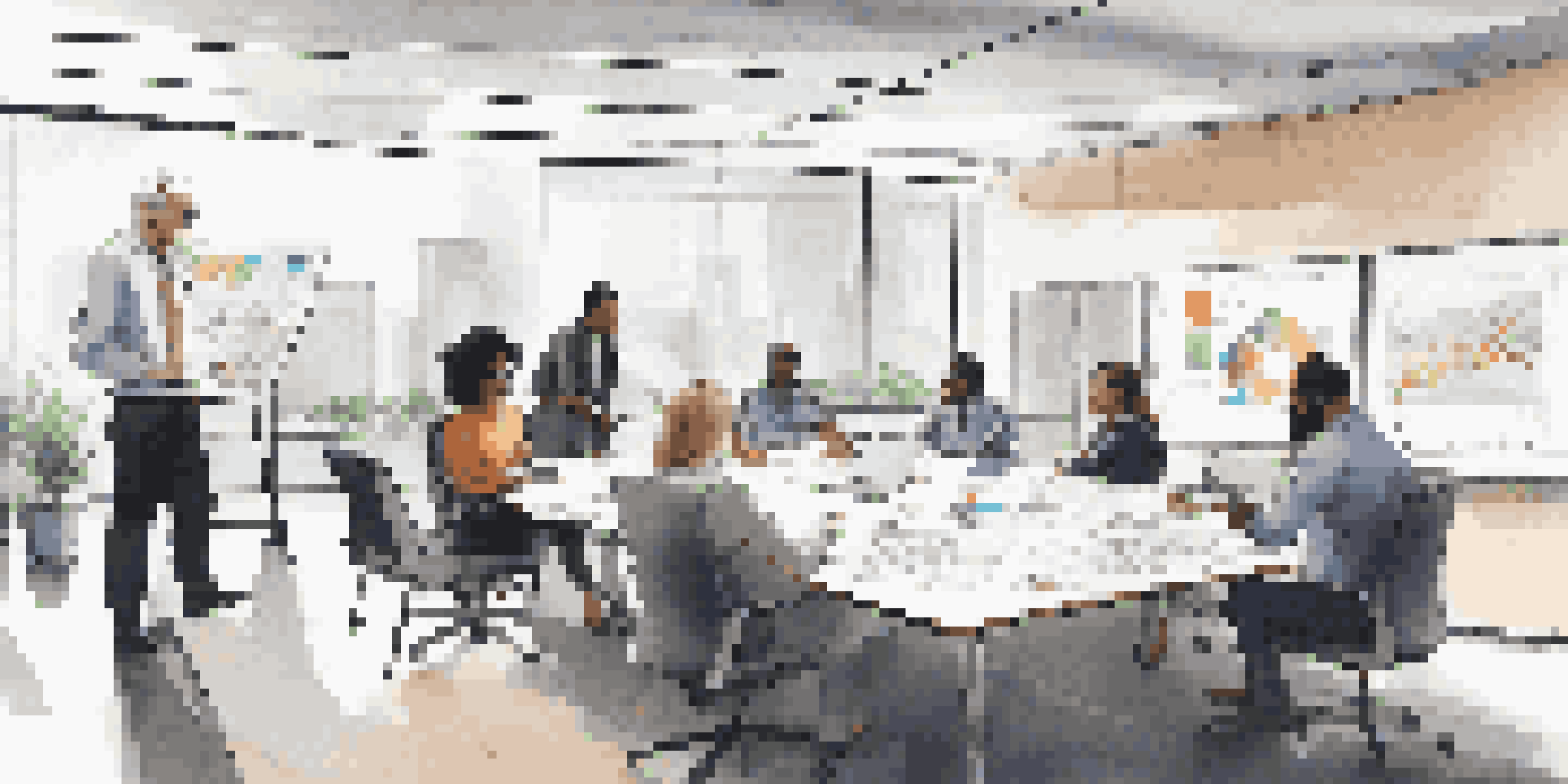 A diverse group of professionals in a modern office discussing business continuity plans with charts and notes visible.