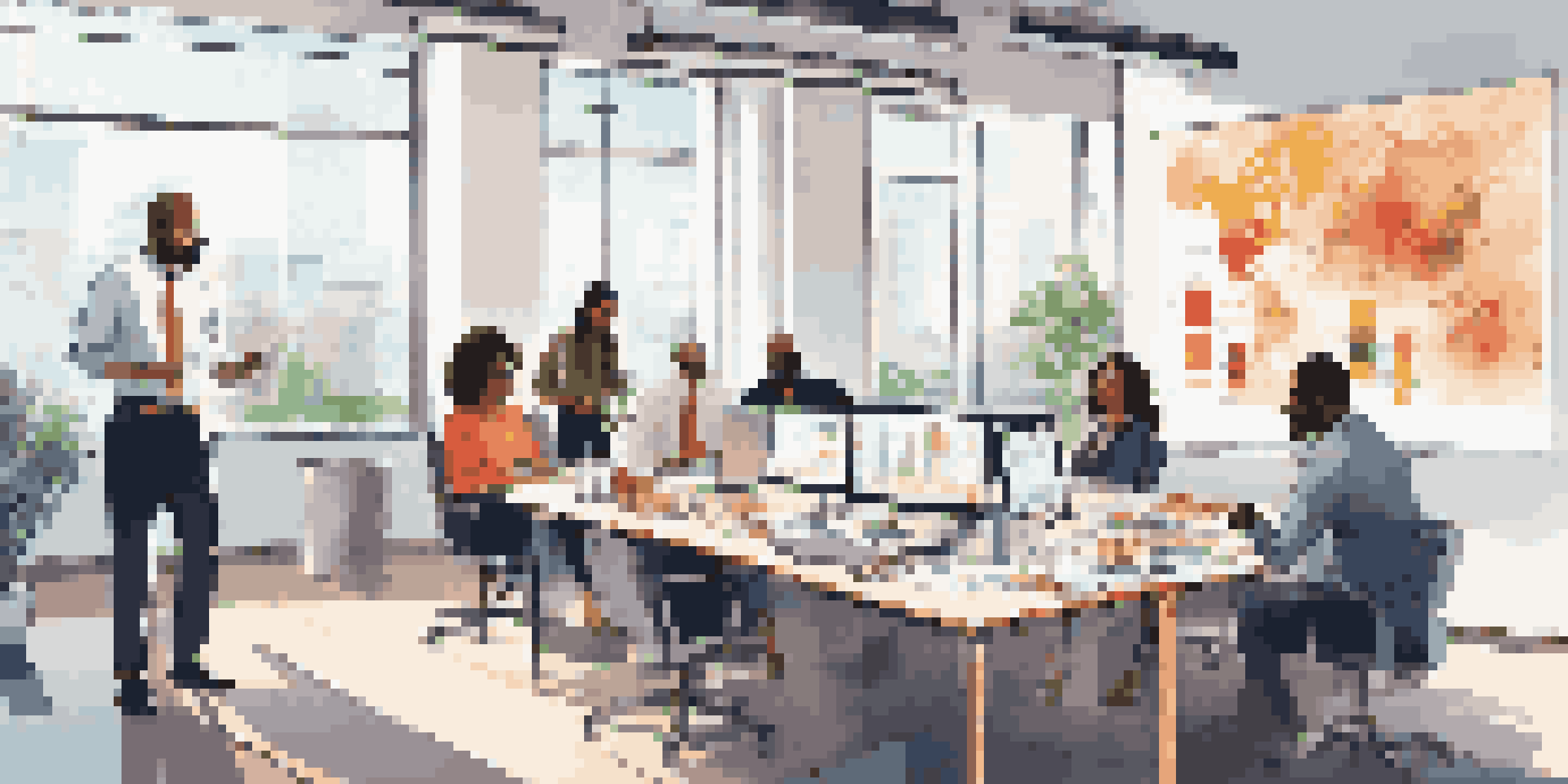 A diverse sales team in a bright office discussing goals and strategies around a large table.