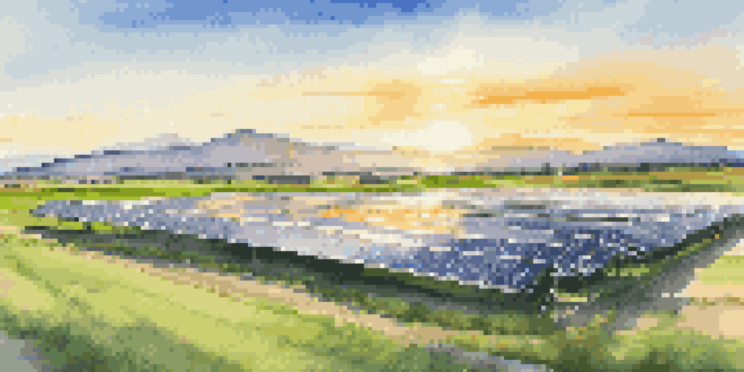 A solar energy farm with green fields and a sunset sky, highlighting the balance between technology and nature.