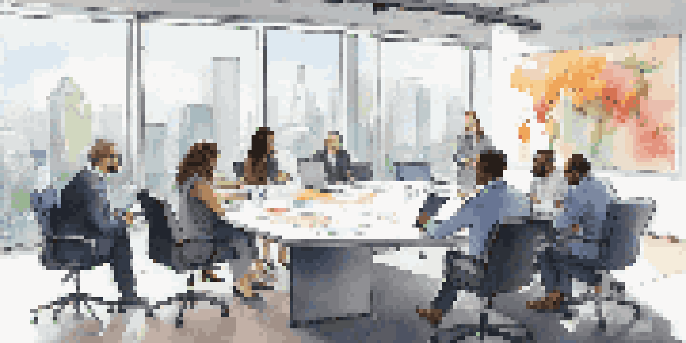 A diverse group of professionals in a bright conference room, discussing strategies with laptops and documents on the table.