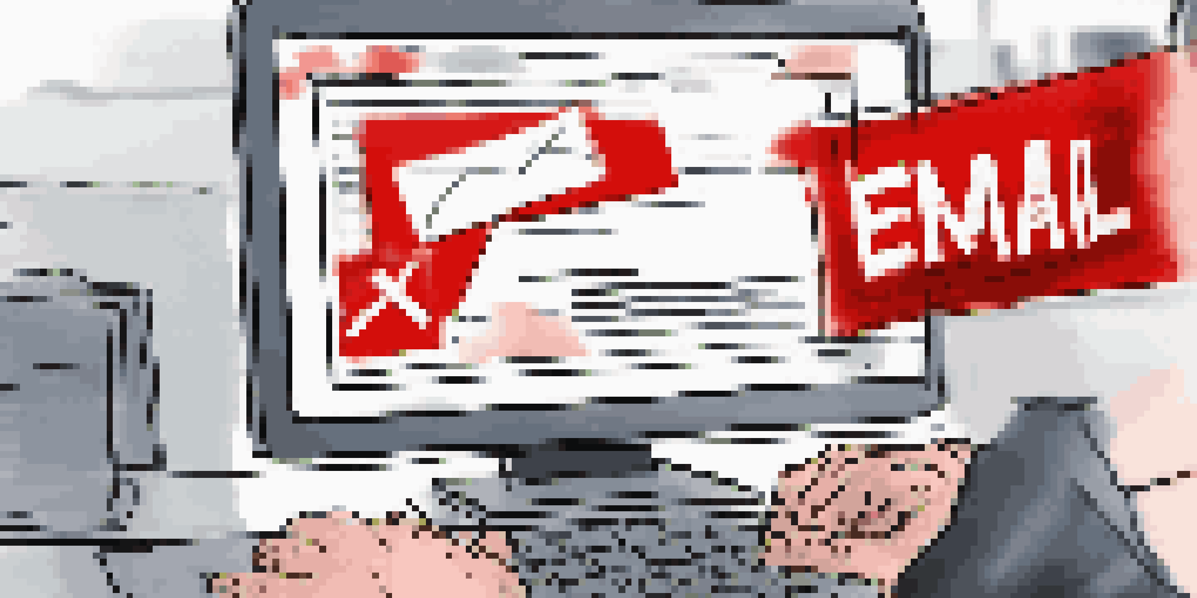 A close-up of a computer screen showing a suspicious email with a warning banner, and a hand hovering over the mouse in a modern office.