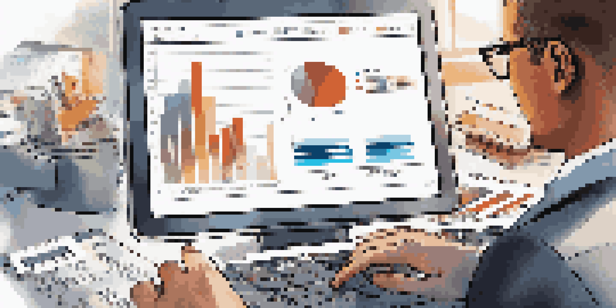 A business professional looking at financial graphs on a tablet in a modern office, with documents and a laptop around them.