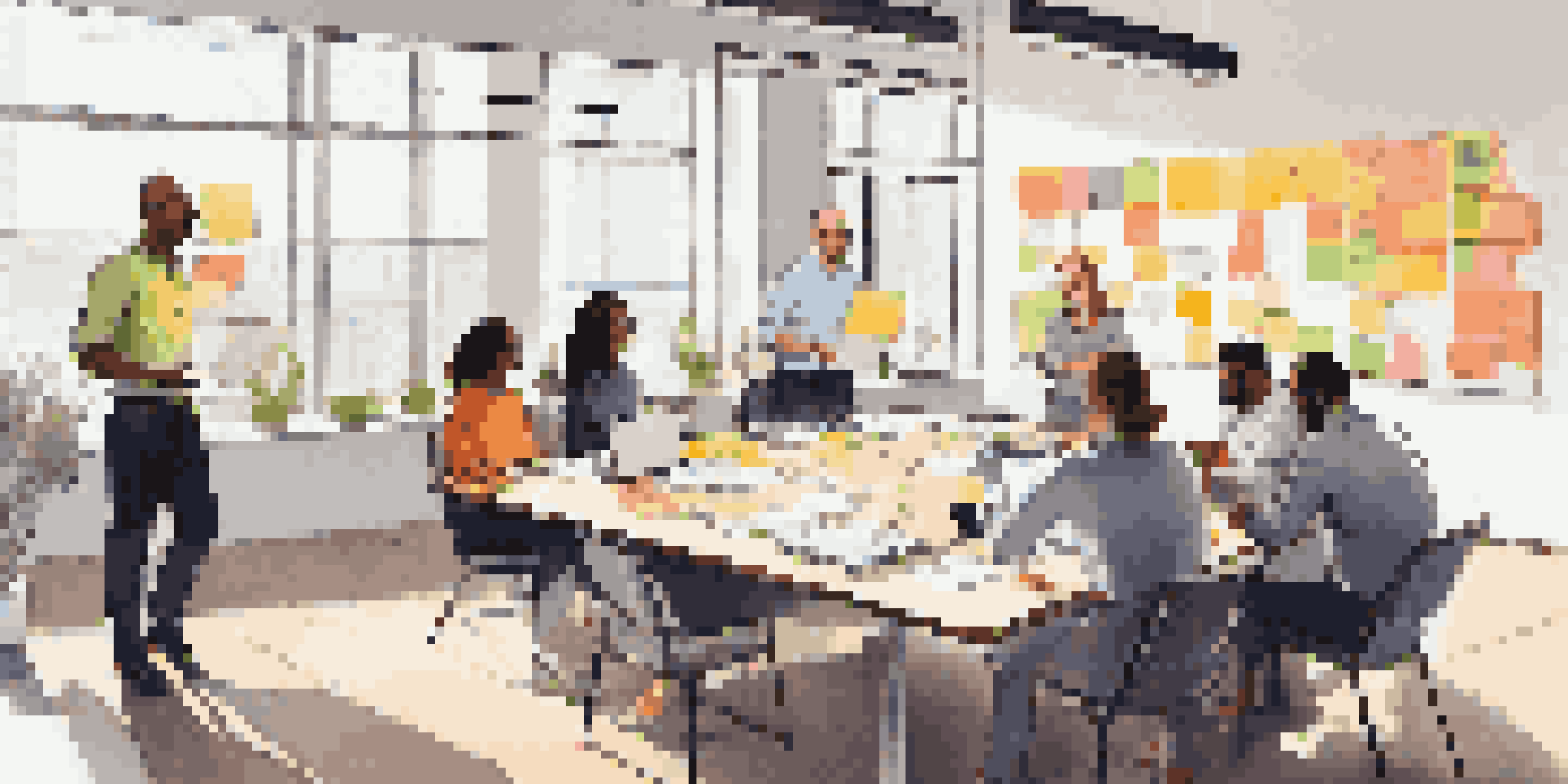 A diverse team of project managers collaborates around a table, with sticky notes and laptops, in a brightly lit room.