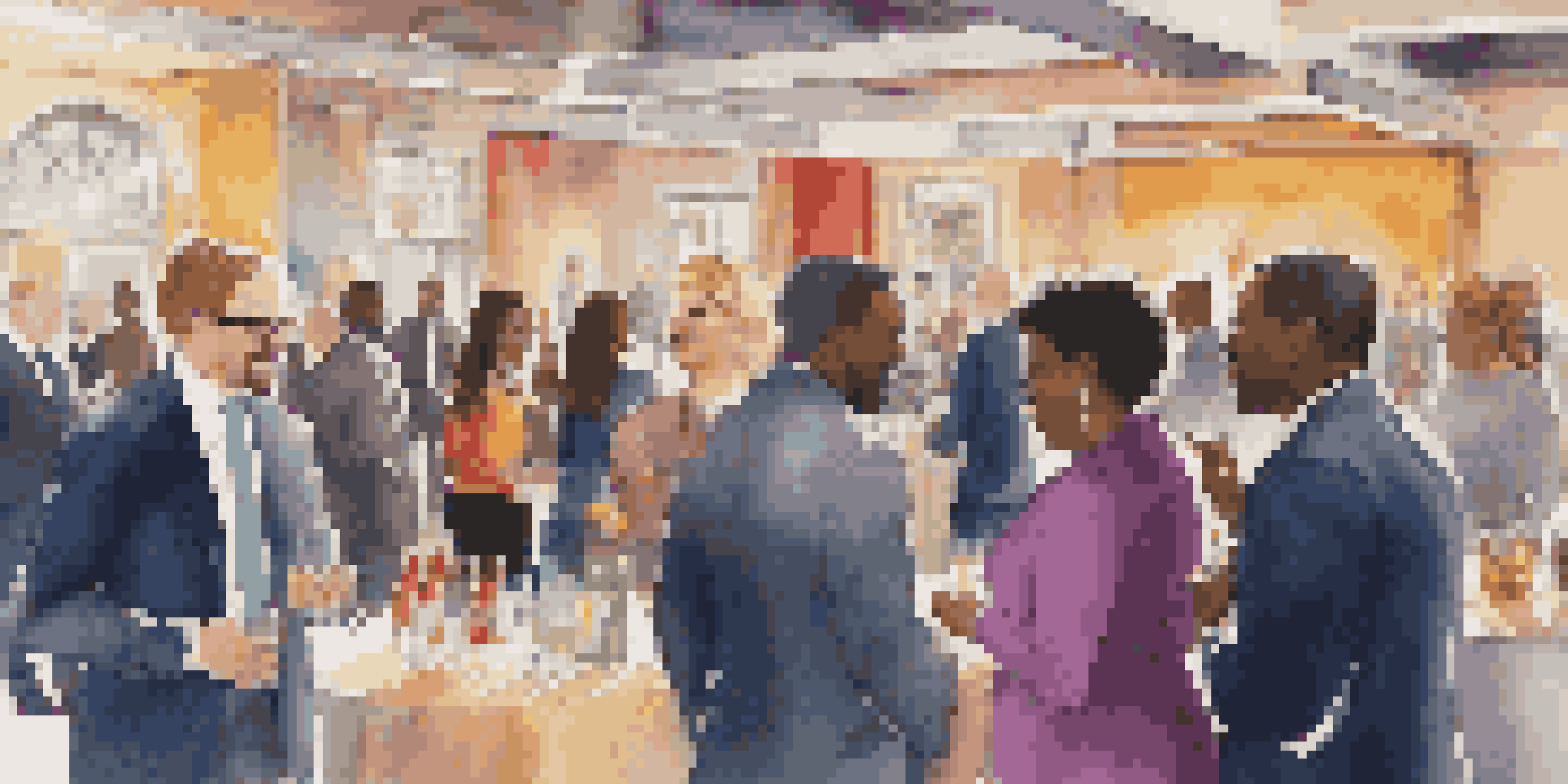 A diverse group of professionals networking at an event, smiling and exchanging business cards in a well-lit venue.