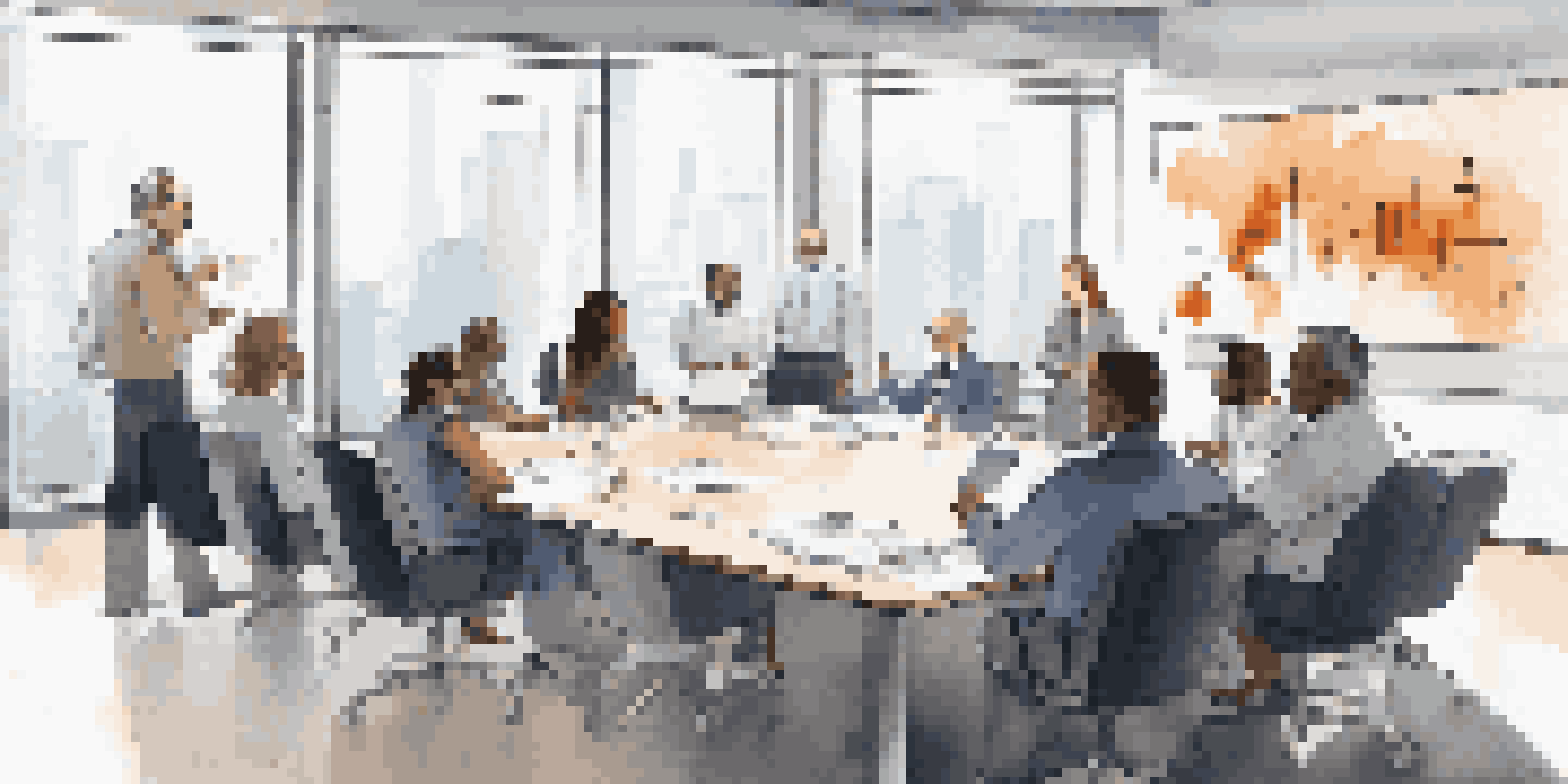 A group of diverse professionals in a bright conference room discussing merger strategies with charts on a screen.