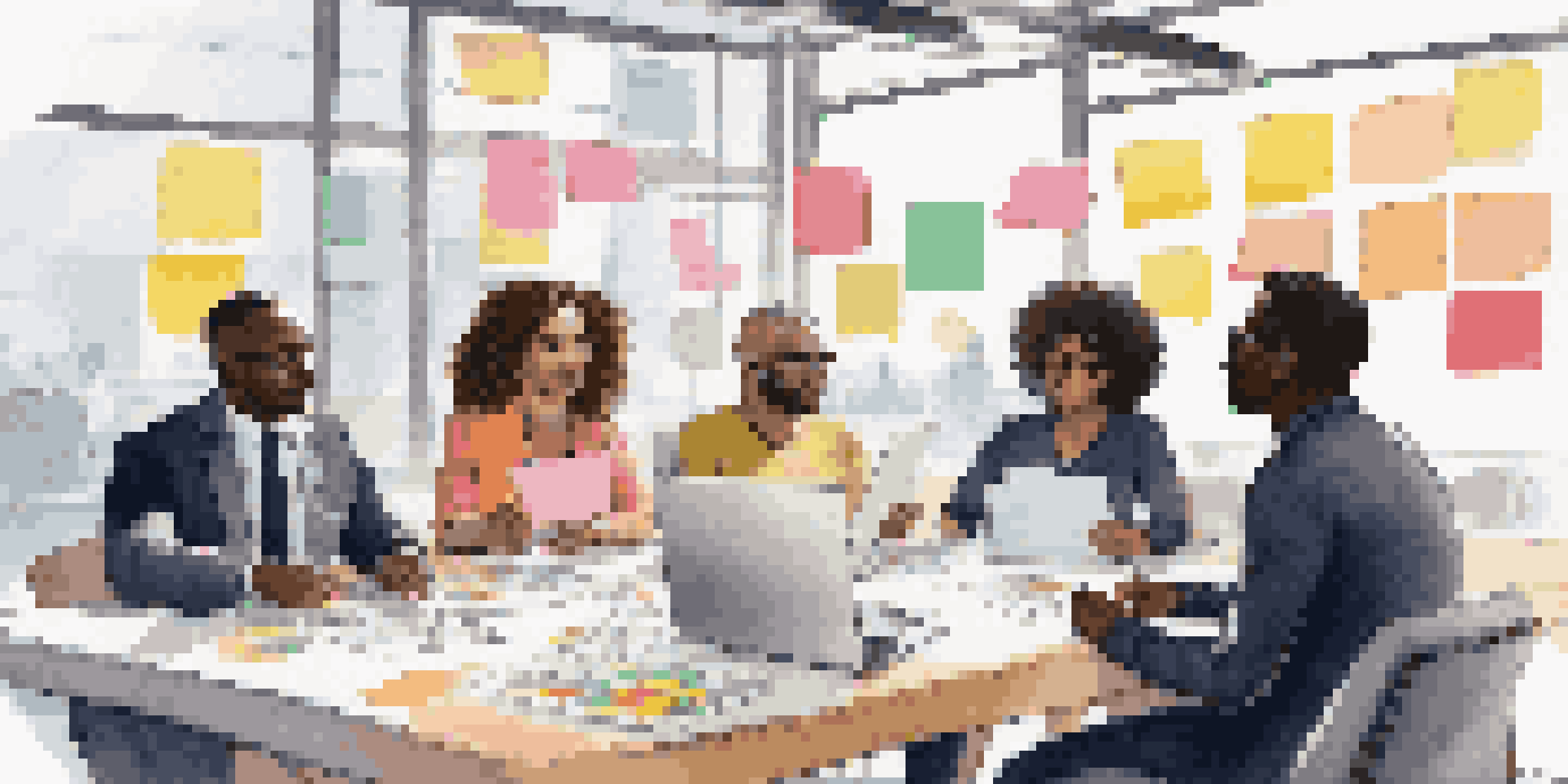 A group of diverse professionals collaborating around a table, engaged in a brainstorming session with post-it notes and laptops.