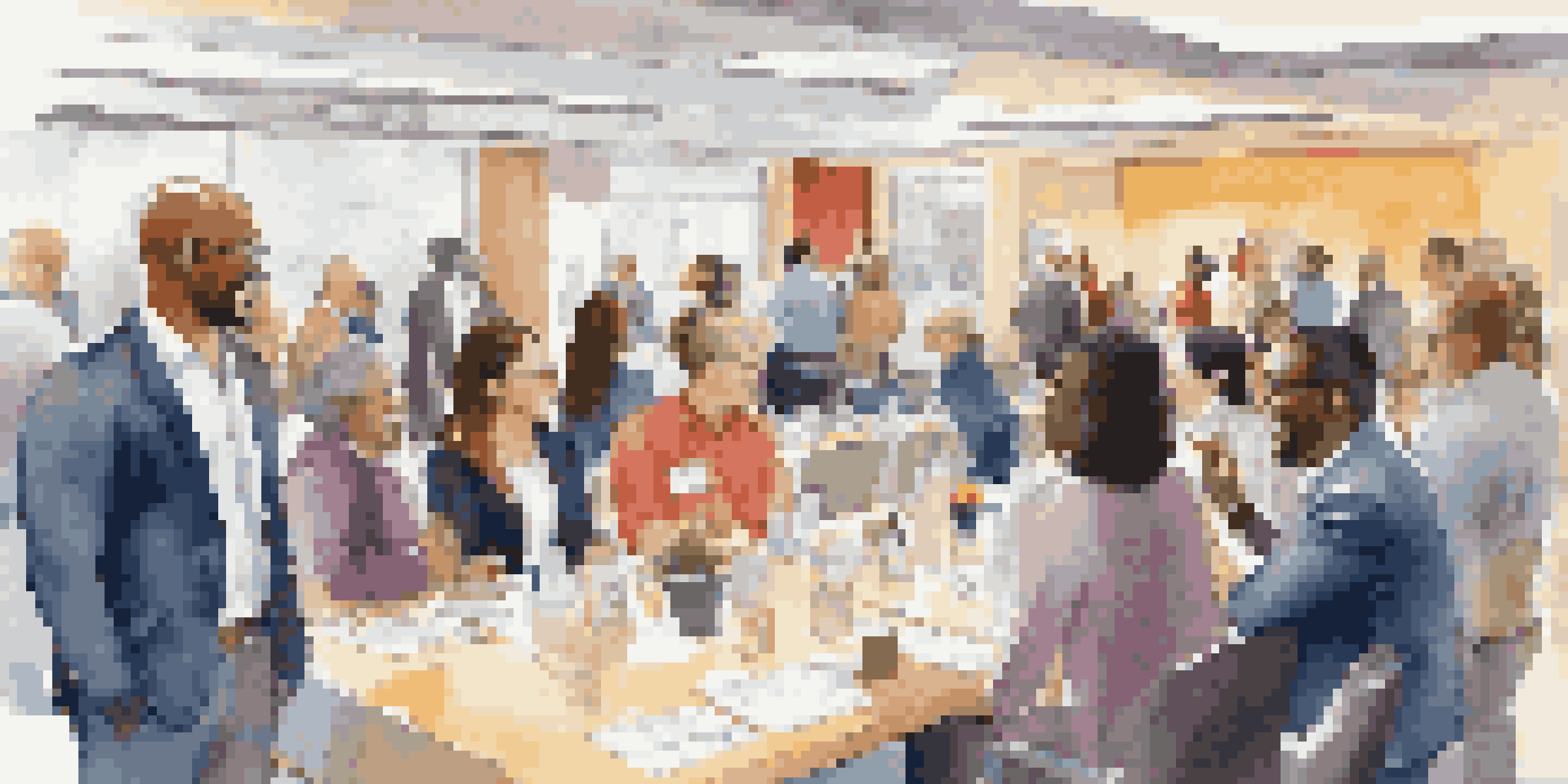A diverse group of professionals networking in a bright conference room, exchanging business cards and smiling.