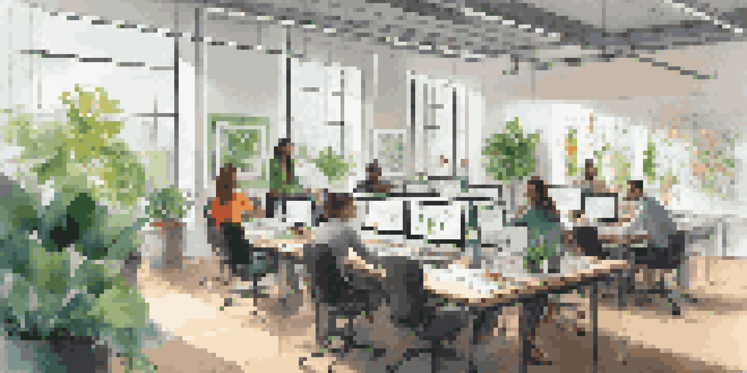 A diverse group of professionals working together in a bright modern office with plants and colorful artwork.