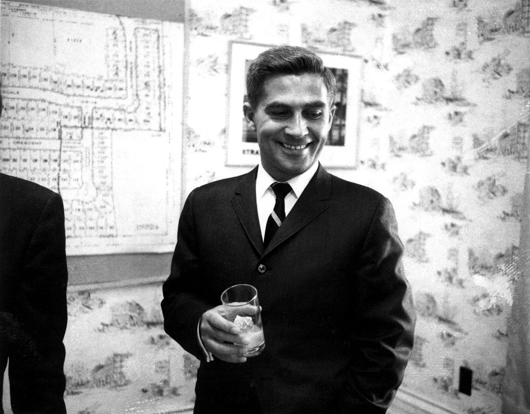 Archival photo of a man in a suit beside a site plan