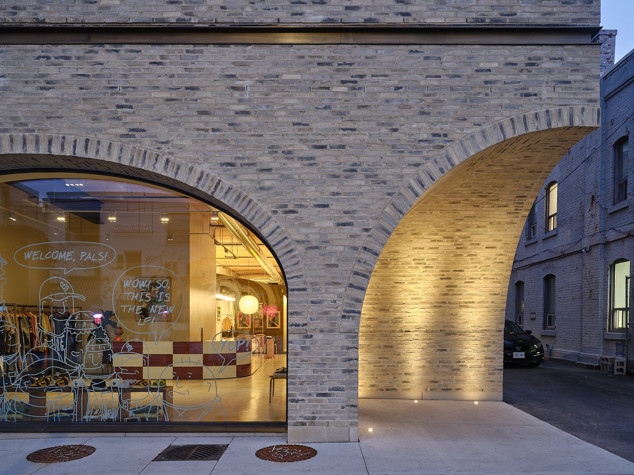 Lit brick archway beside a shopfront at dusk