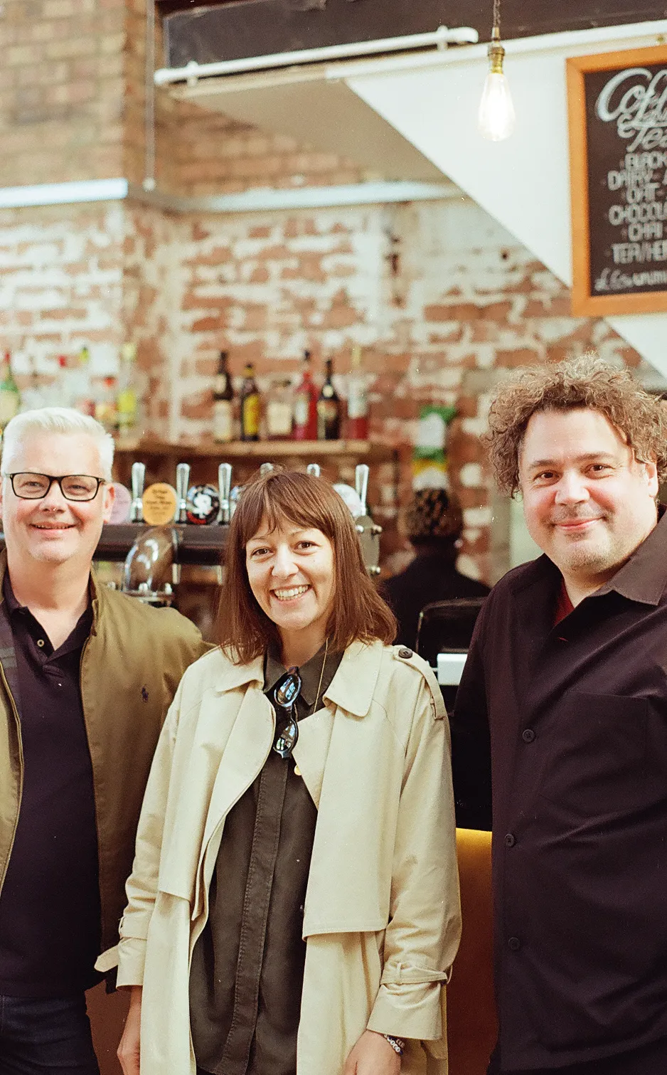 Three people in a brick-walled café