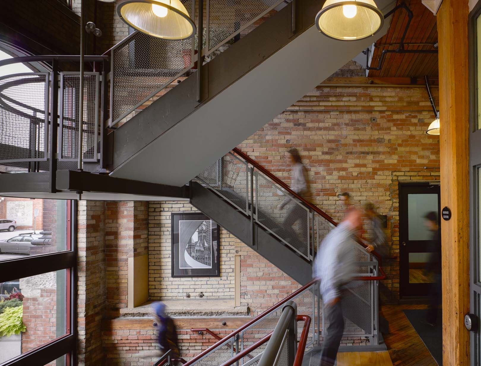 People on a steel stair in a brick atrium