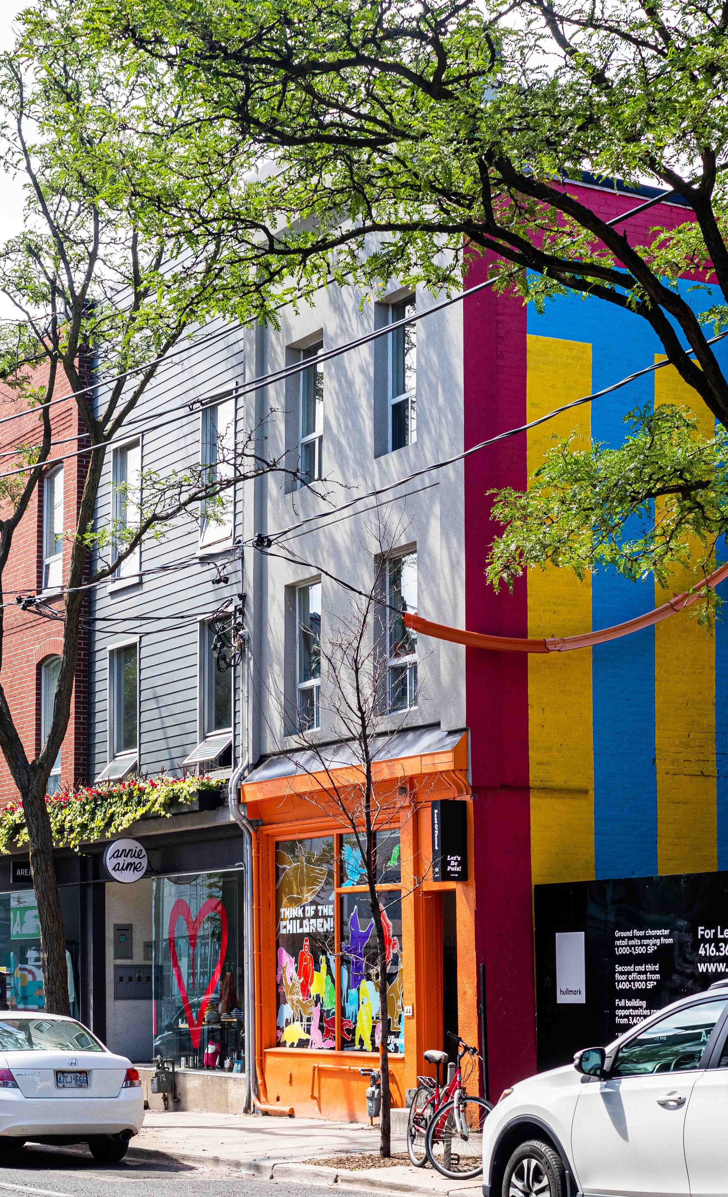 Storefronts below a bright striped wall mural
