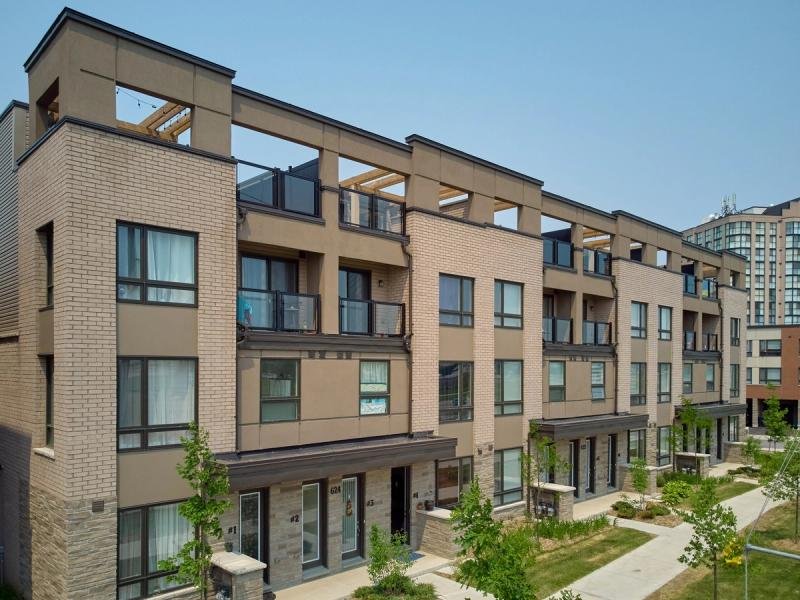Row of beige brick townhomes with rooftop decks