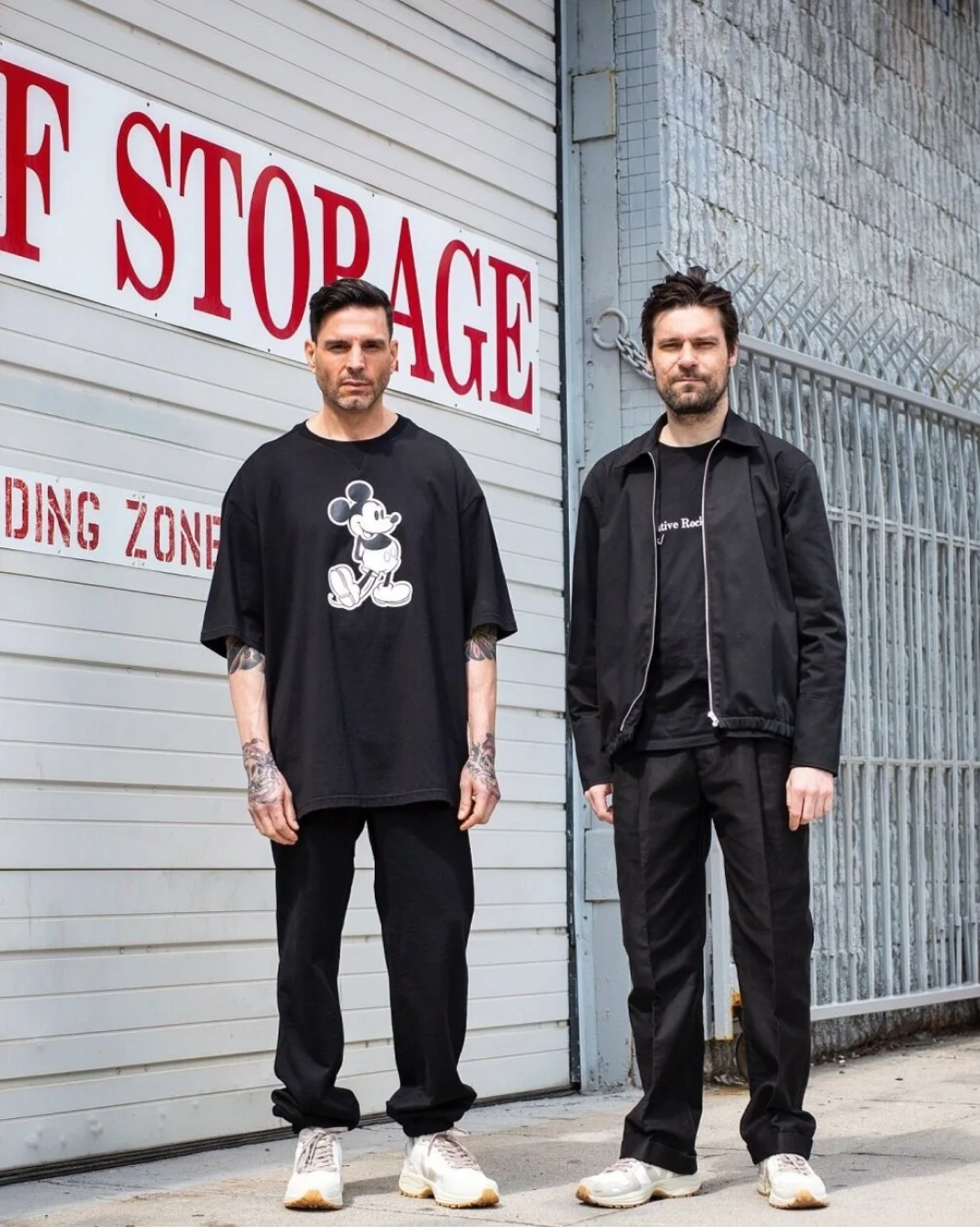 Two people in black outside a storage building