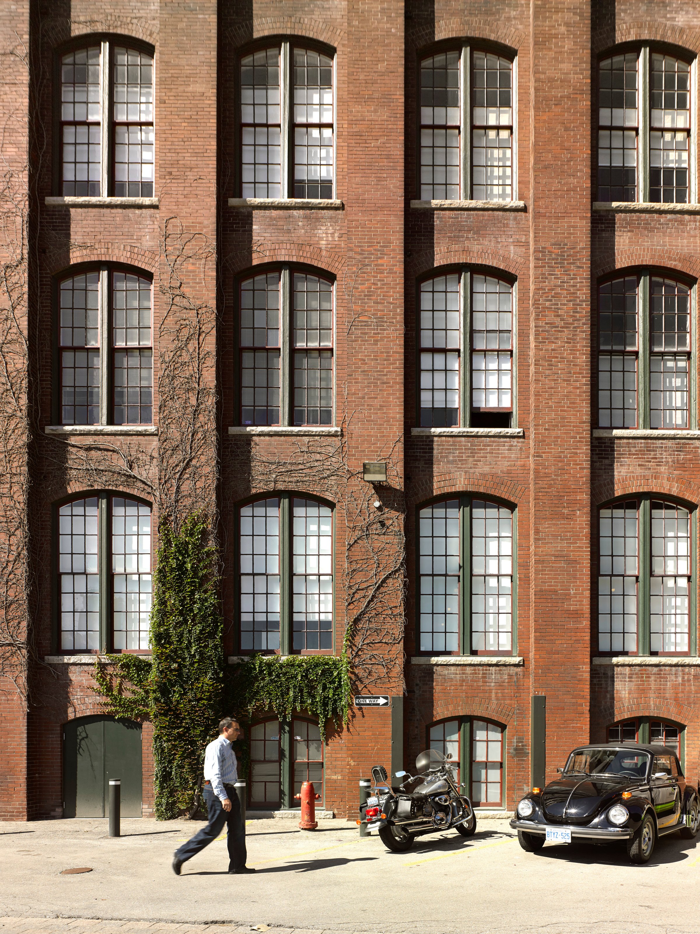 A person walks past an arched-window brick facade