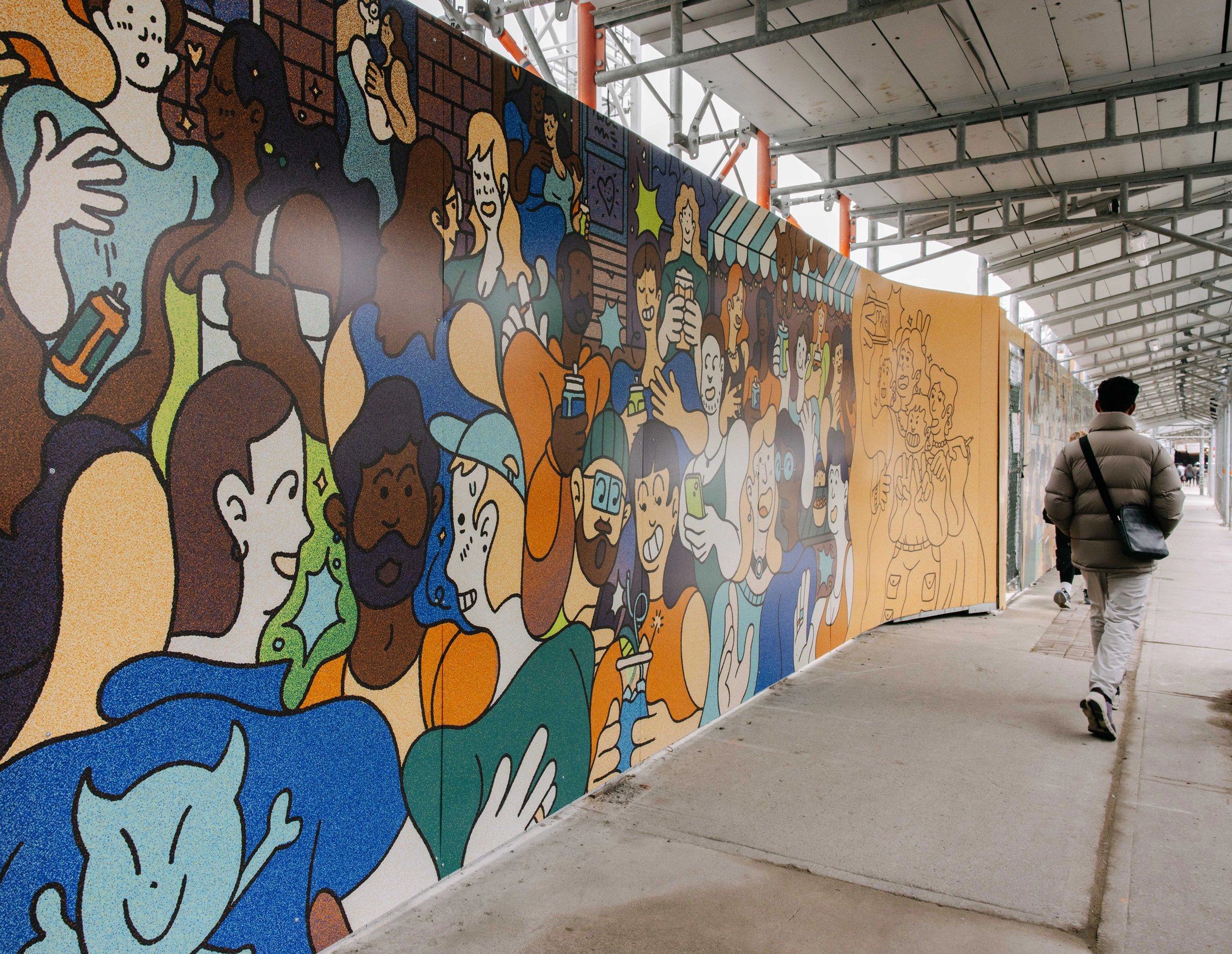 A person walks past a mural on a hoarding