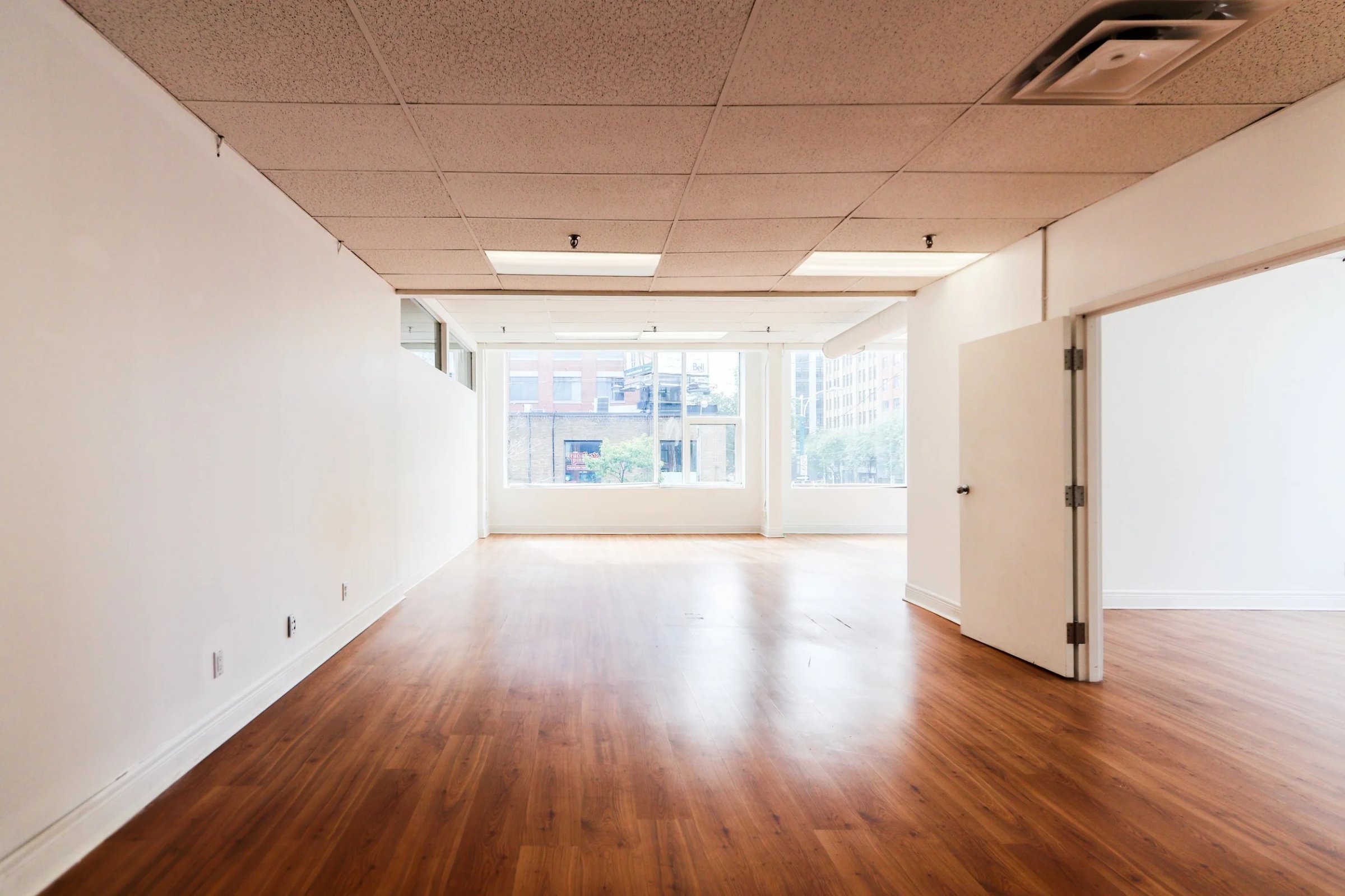 Bare office room with wood floor, drop ceiling