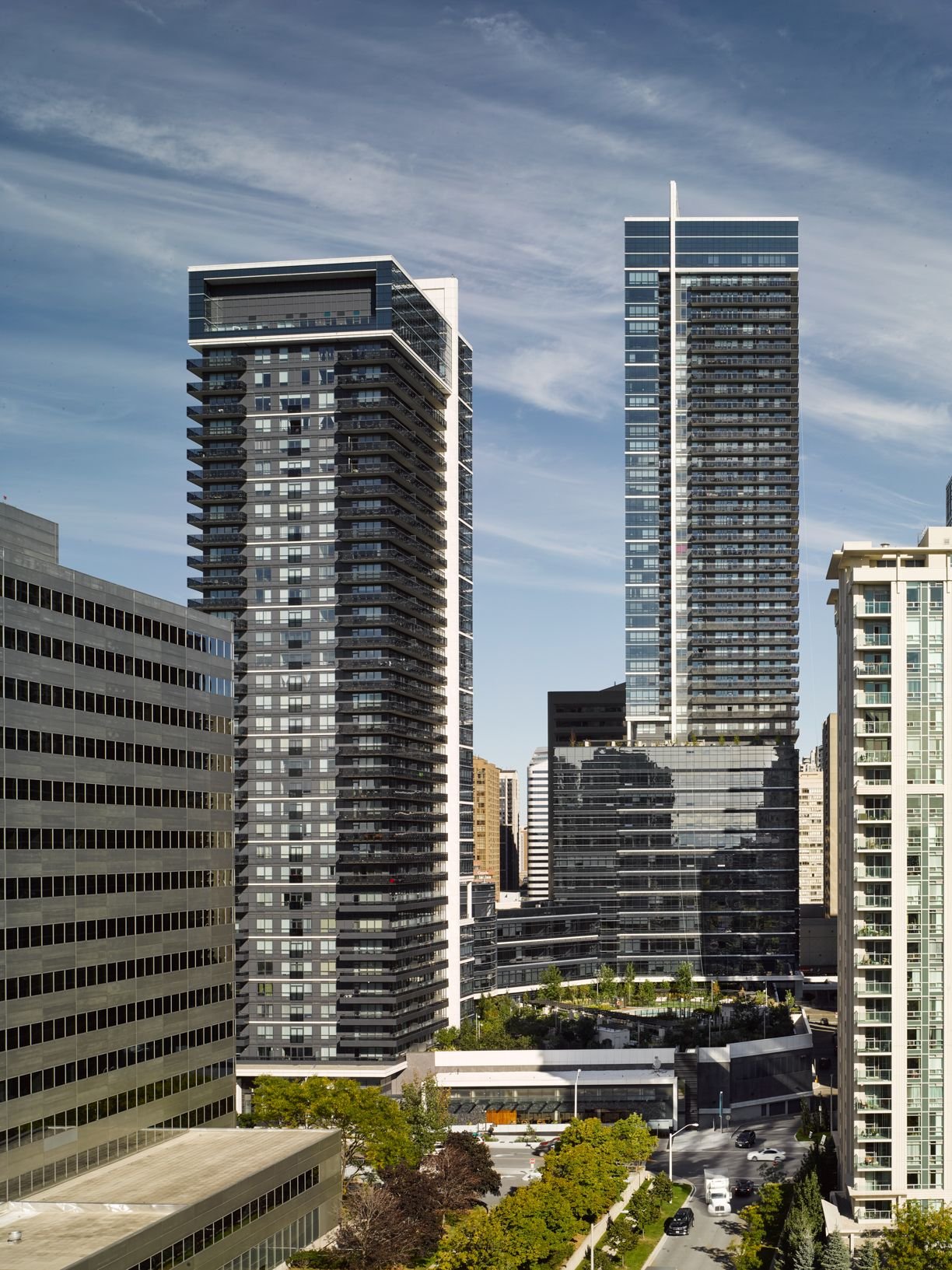 Two glass condo towers over a green podium