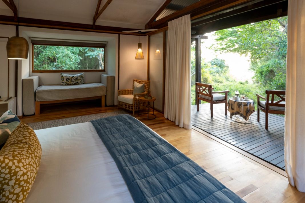 A family room with a window seat and doors open to a private deck set with morning tea.