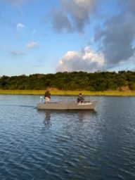A guide and a guest cross calm estuary water in one of the lodge's small boats.