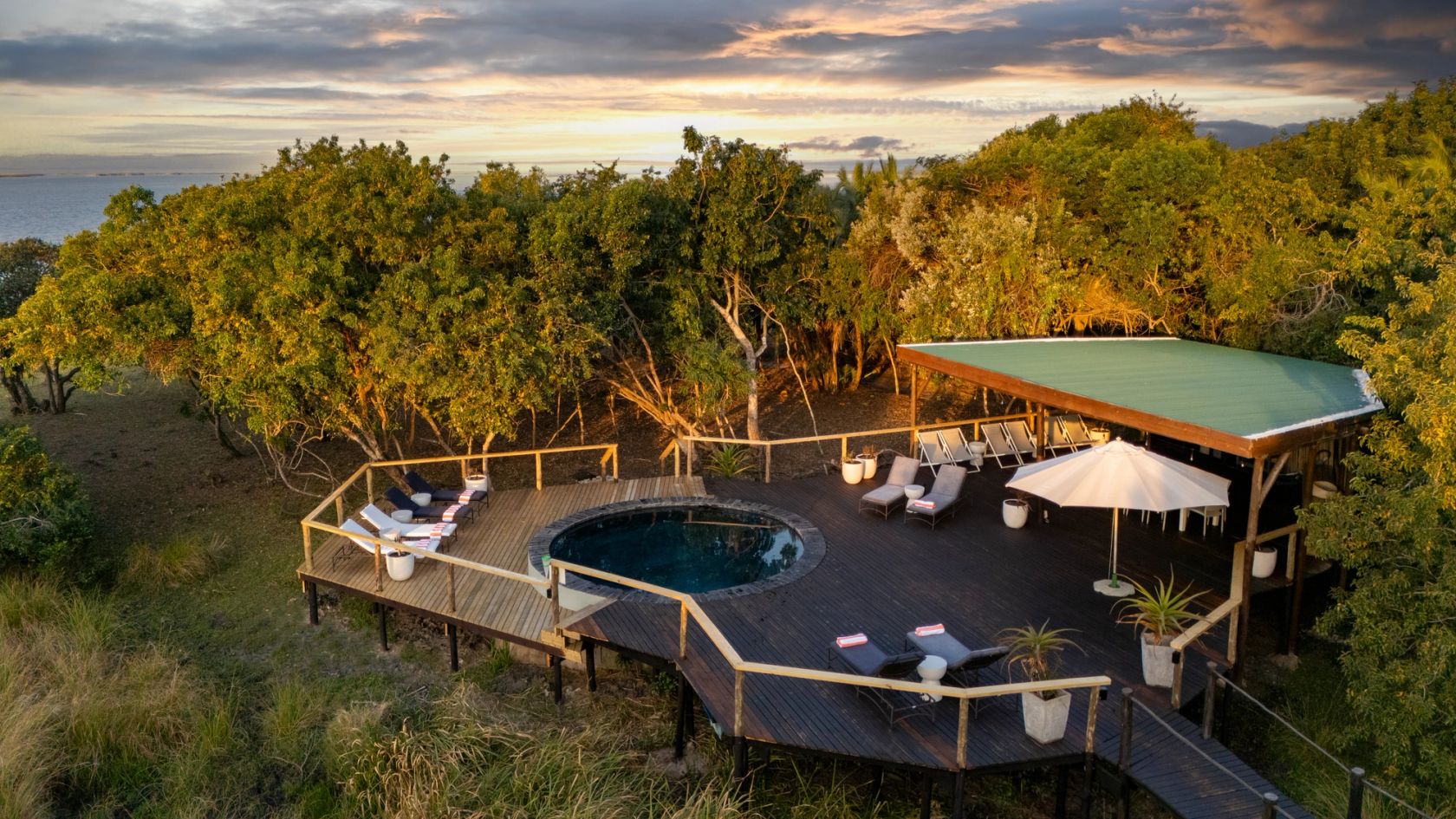 The pool deck and shaded lounge at golden hour, with Lake St Lucia beyond the trees.