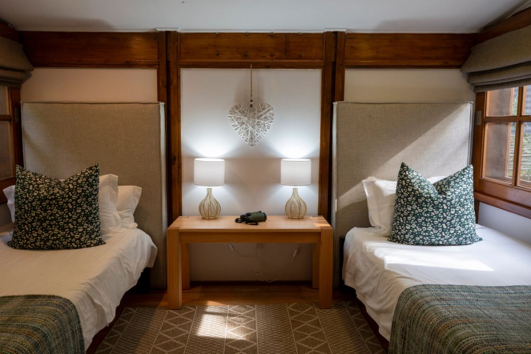 Twin beds in a family room, with lamps and a shared bedside table between them.