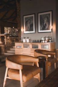 Two leather tub chairs beside a coffee station under framed black-and-white leopard photographs.
