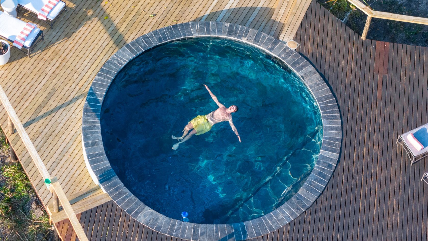 A guest floats on his back in the circular plunge pool, seen from directly overhead.