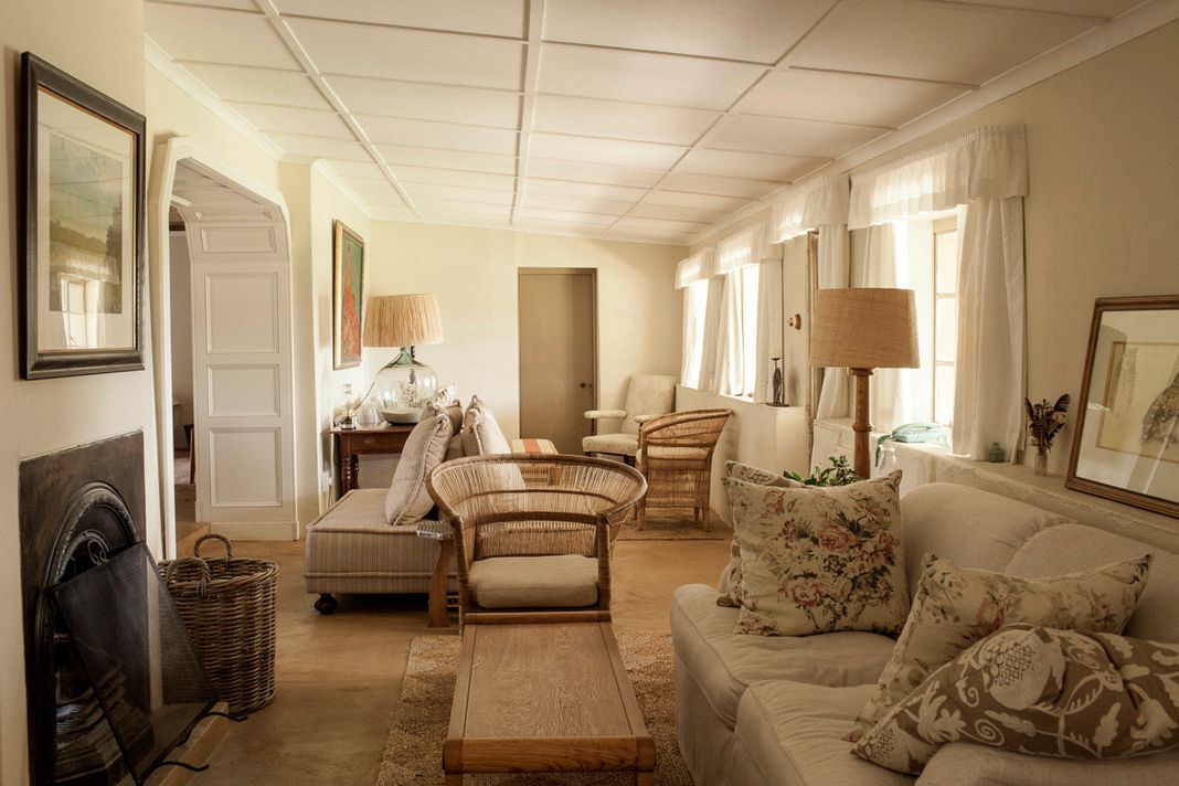 Sitting room in the Umzinyathi farmhouse with sofas, cushions, a fireplace, and framed pictures.