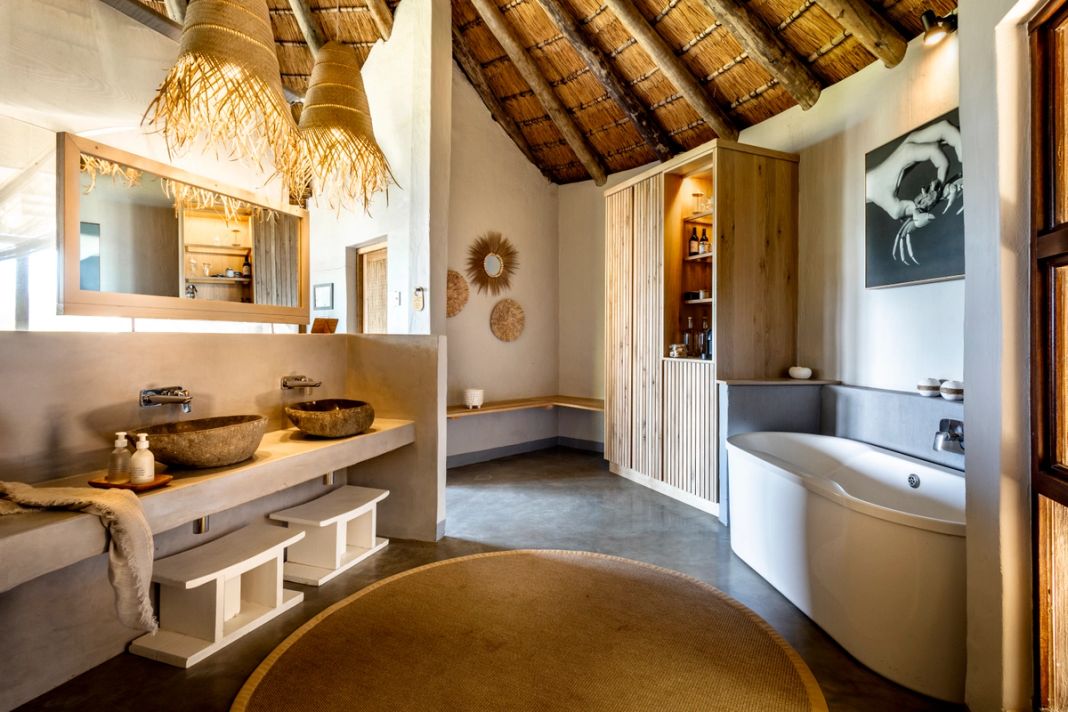 An en-suite bathroom with twin stone basins, a freestanding tub and a black-and-white crab photograph.