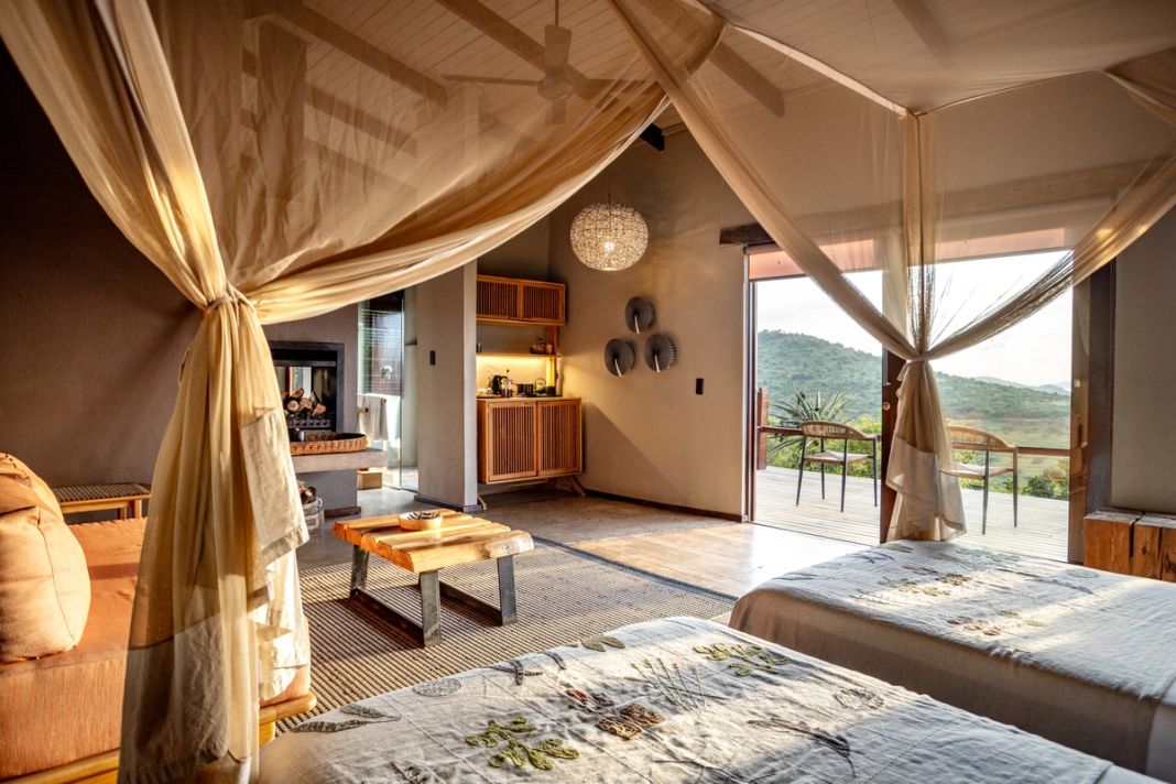 A family suite with a four-poster and a second bed, an in-room fireplace and kitchenette, doors open to a deck.