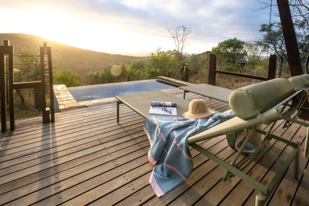 A honeymoon villa deck at sunrise with a private plunge pool and loungers looking over the bushveld.