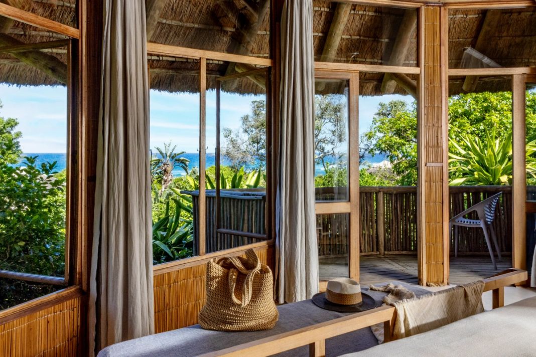 A cushioned window bench looking through corner windows across the deck to the Indian Ocean.