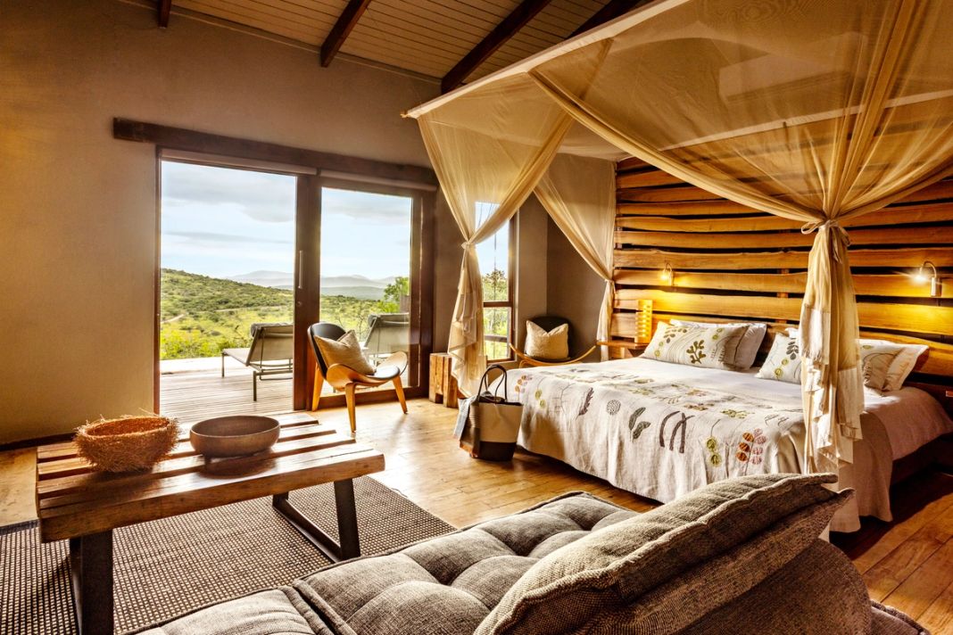 Villa bedroom with a canopy bed, a live-edge headboard, a chaise and glass doors to a view deck.