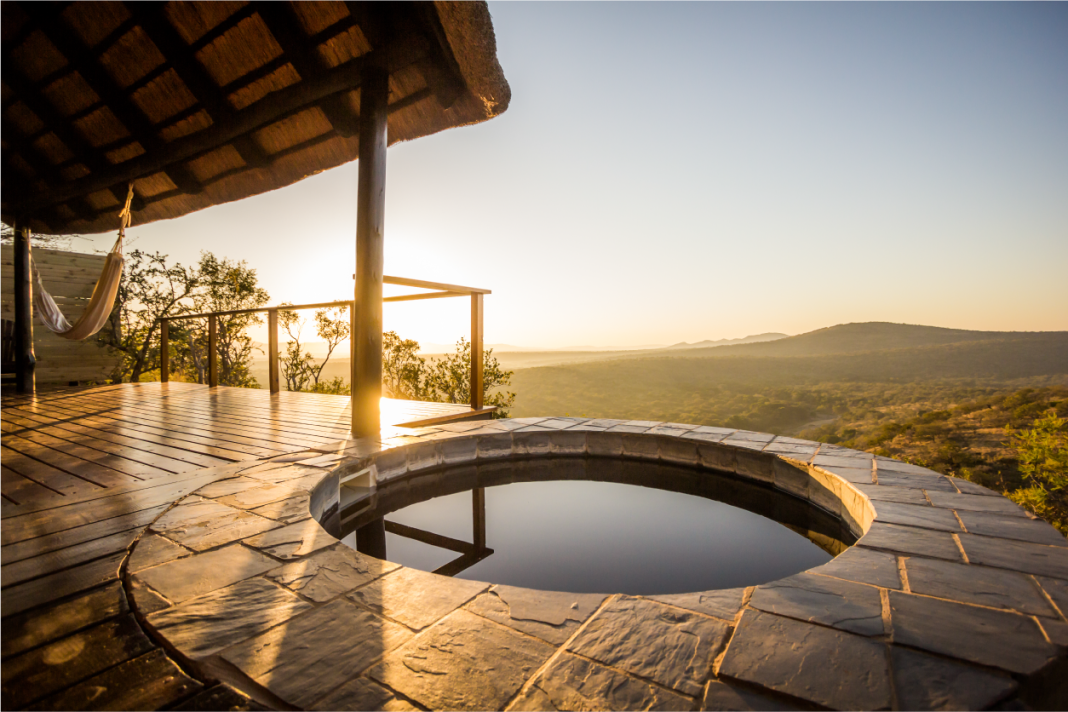 A circular stone plunge pool on a thatched suite deck overlooks the valley in low golden light.