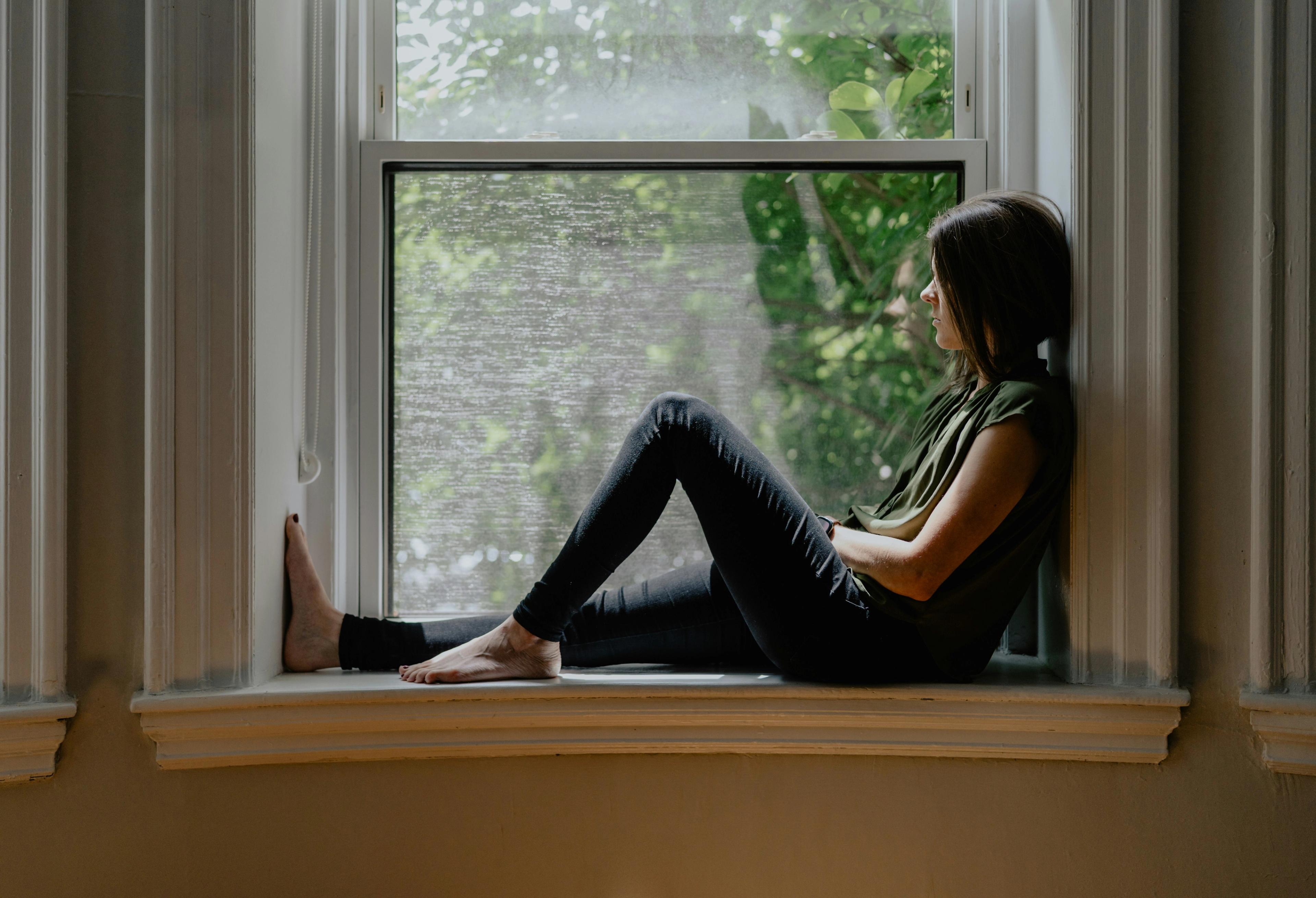 A woman next to a window thinking