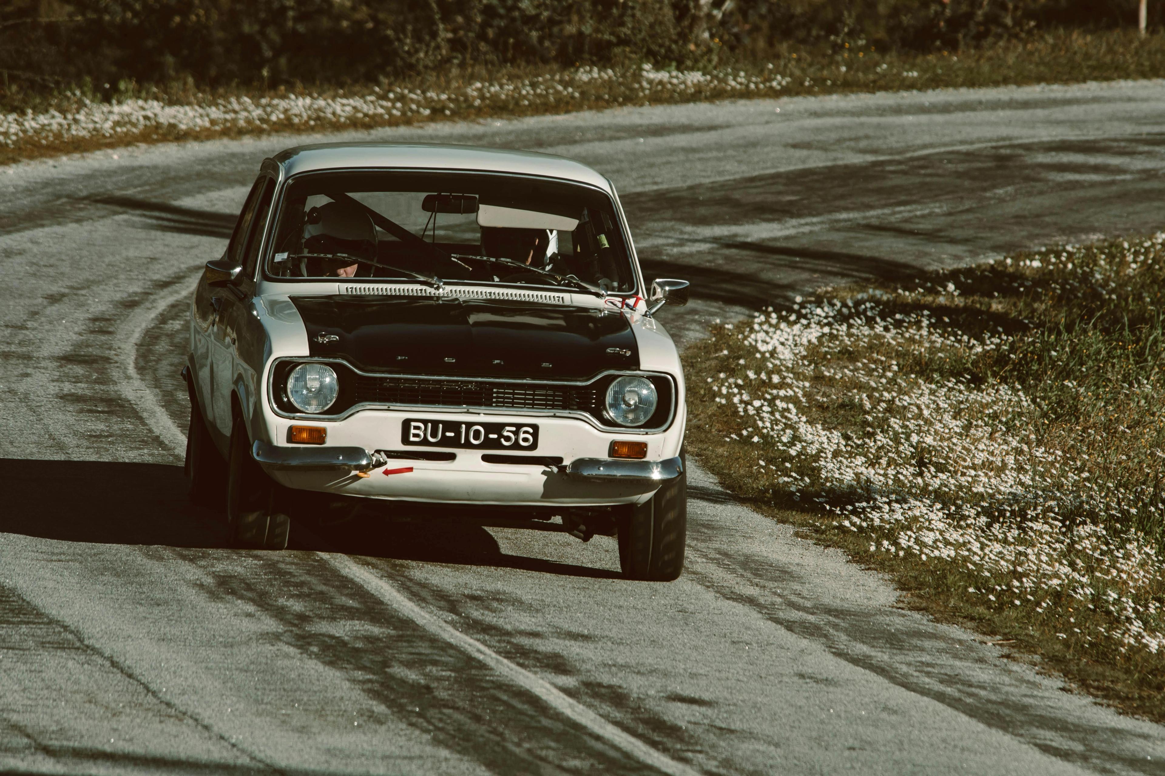 An old car driving down a road
