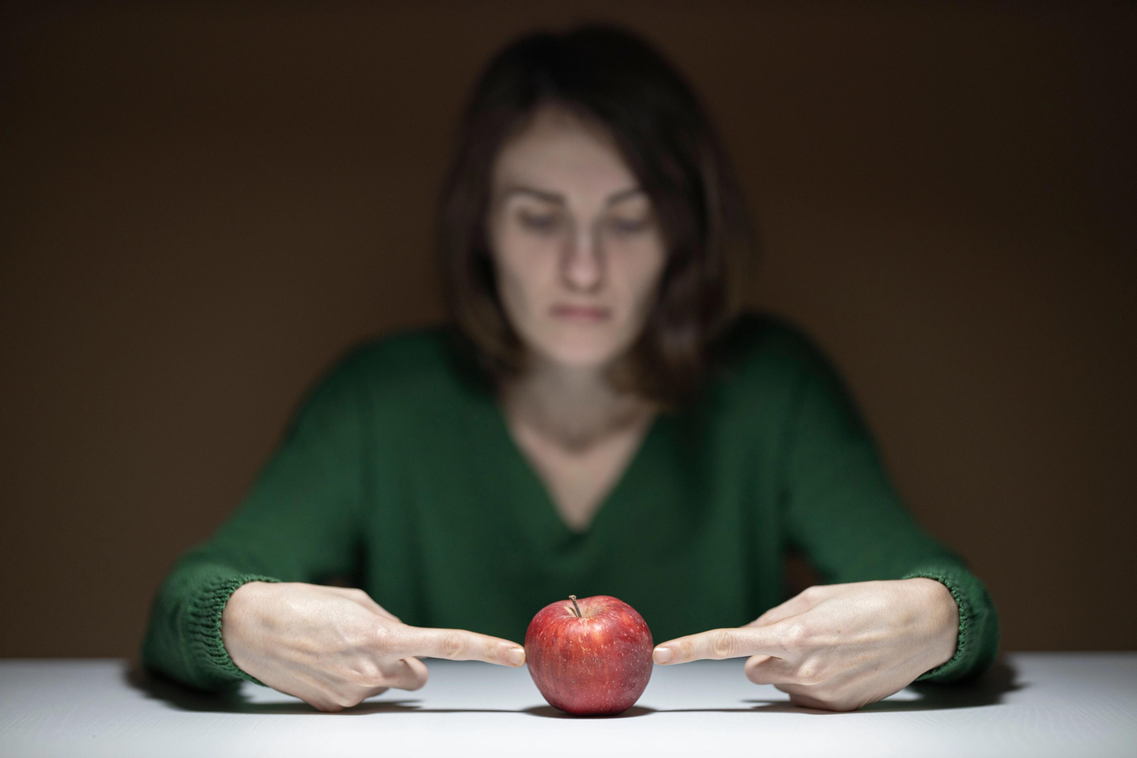 Someone pointing to an apple whilst thinking